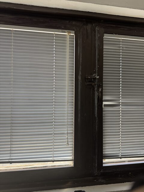 A window frame thickly painted and packed by hand in repeated repairs
